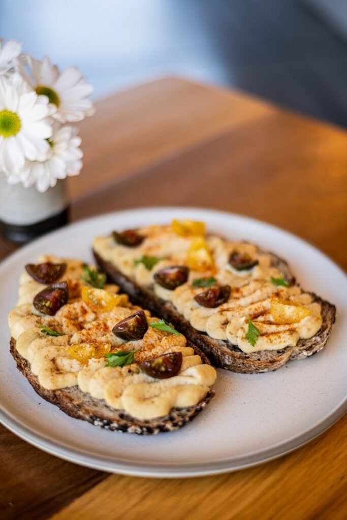Delicious gourmet hummus crostini with cherry tomatoes and herbs, styled neatly on a plate.